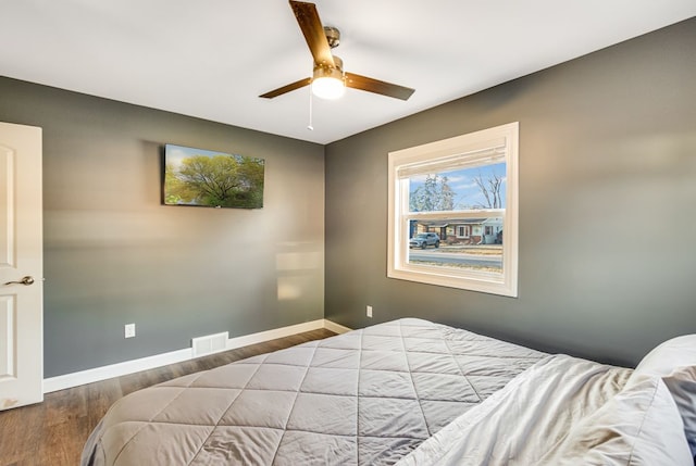 bedroom featuring visible vents, ceiling fan, baseboards, and wood finished floors