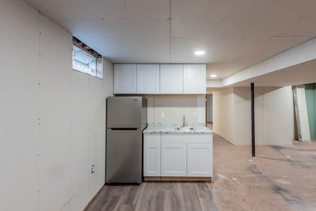 kitchen with a sink, light wood-type flooring, white cabinets, and freestanding refrigerator