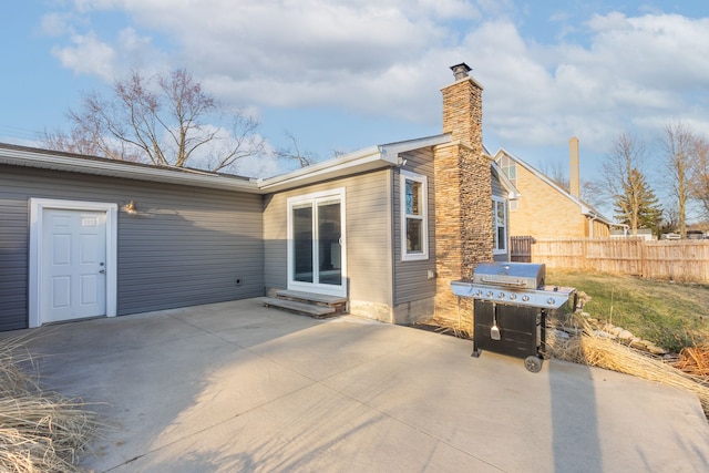 exterior space with fence, a chimney, entry steps, and a patio area