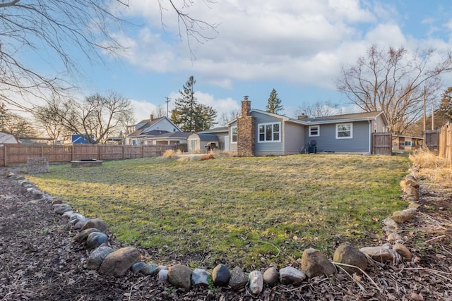 rear view of house featuring a yard, a chimney, and a fenced backyard