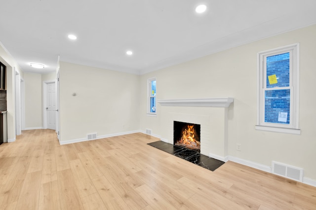 unfurnished living room with visible vents, light wood-style flooring, a fireplace, and baseboards