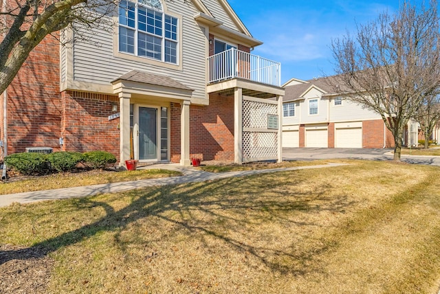 view of front of home featuring a garage, a front yard, brick siding, and a balcony