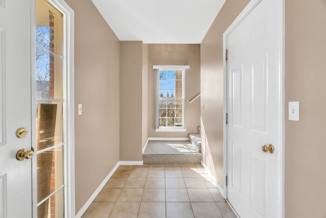 corridor with stairs, light tile patterned floors, and baseboards