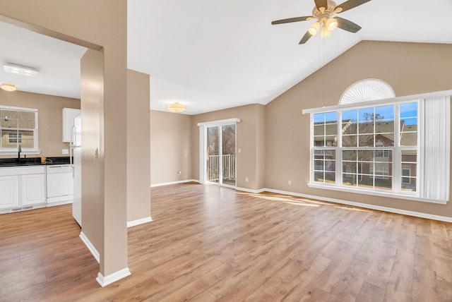 unfurnished living room with lofted ceiling, a ceiling fan, light wood finished floors, and a sink