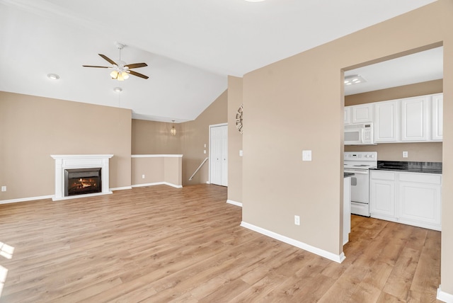 unfurnished living room with light wood-style flooring, a ceiling fan, a lit fireplace, baseboards, and vaulted ceiling