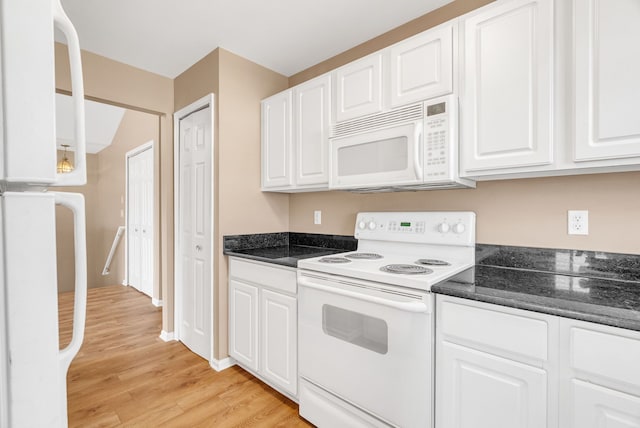 kitchen with white cabinetry, white appliances, dark stone countertops, and light wood-type flooring