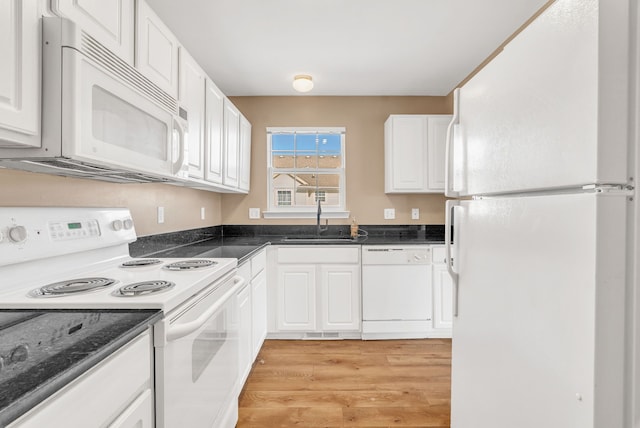 kitchen with white appliances, light wood finished floors, a sink, white cabinetry, and dark countertops