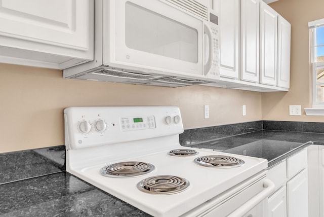 kitchen with white appliances, white cabinets, and dark countertops