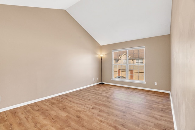 unfurnished room with baseboards, light wood finished floors, and high vaulted ceiling