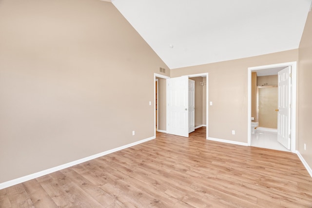 unfurnished bedroom with visible vents, a walk in closet, light wood-style flooring, ensuite bathroom, and baseboards