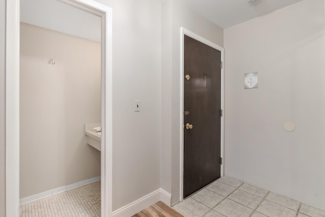 corridor with baseboards and light tile patterned flooring