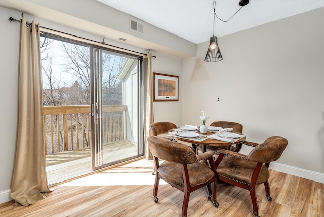 dining space featuring visible vents, light wood-type flooring, and baseboards