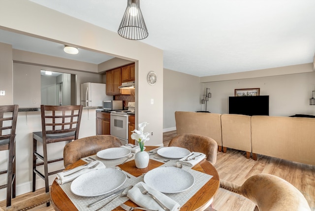 dining space featuring light wood-style flooring and baseboards