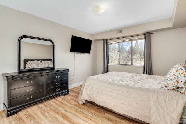 bedroom with visible vents, light wood-style flooring, and baseboards