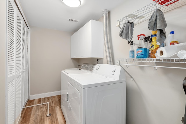 washroom featuring visible vents, baseboards, cabinet space, separate washer and dryer, and light wood-type flooring