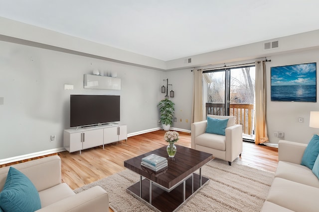 living room featuring wood finished floors, visible vents, and baseboards