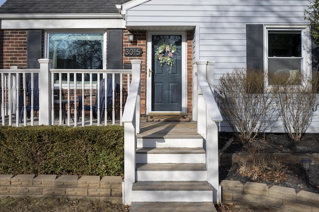 entrance to property featuring a shingled roof