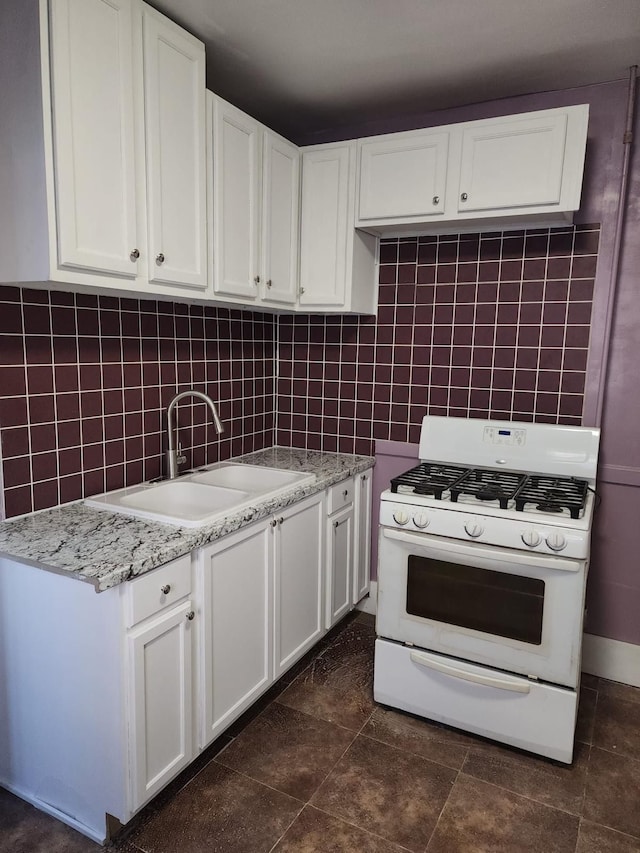 kitchen with white cabinets, tasteful backsplash, white gas range oven, and a sink