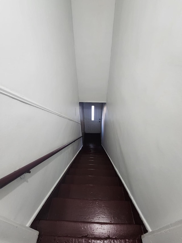 staircase with baseboards, wood finished floors, and vaulted ceiling