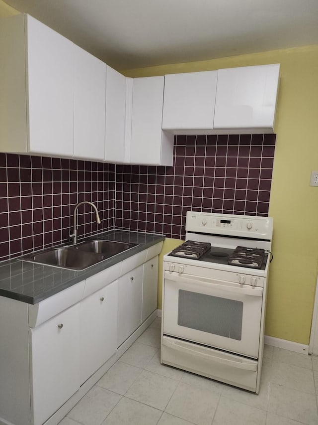 kitchen with white cabinets, white gas stove, tasteful backsplash, and a sink