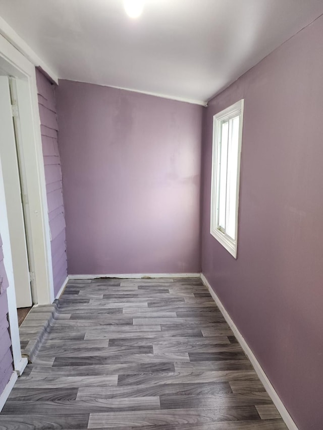 spare room with baseboards and wood finished floors