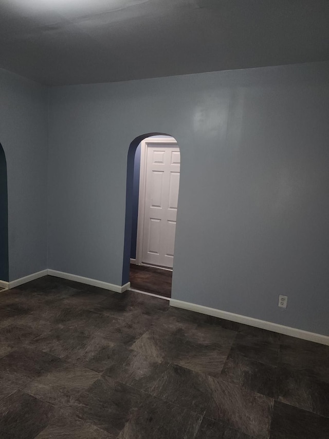unfurnished room with baseboards and arched walkways