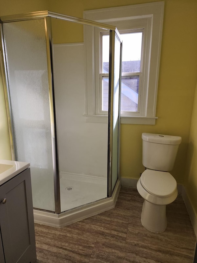 full bathroom with baseboards, toilet, wood finished floors, and a shower stall