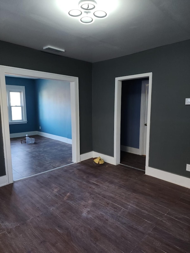unfurnished room featuring visible vents, baseboards, and wood finished floors