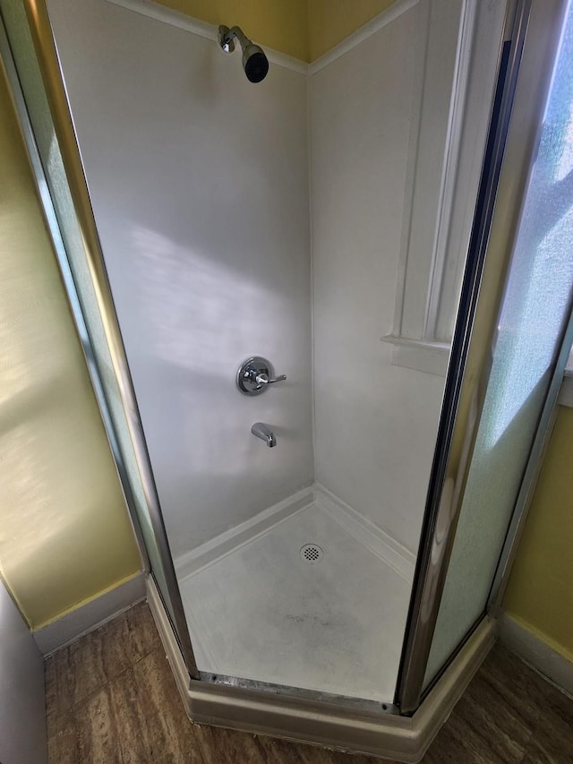 full bathroom featuring wood finished floors and a stall shower