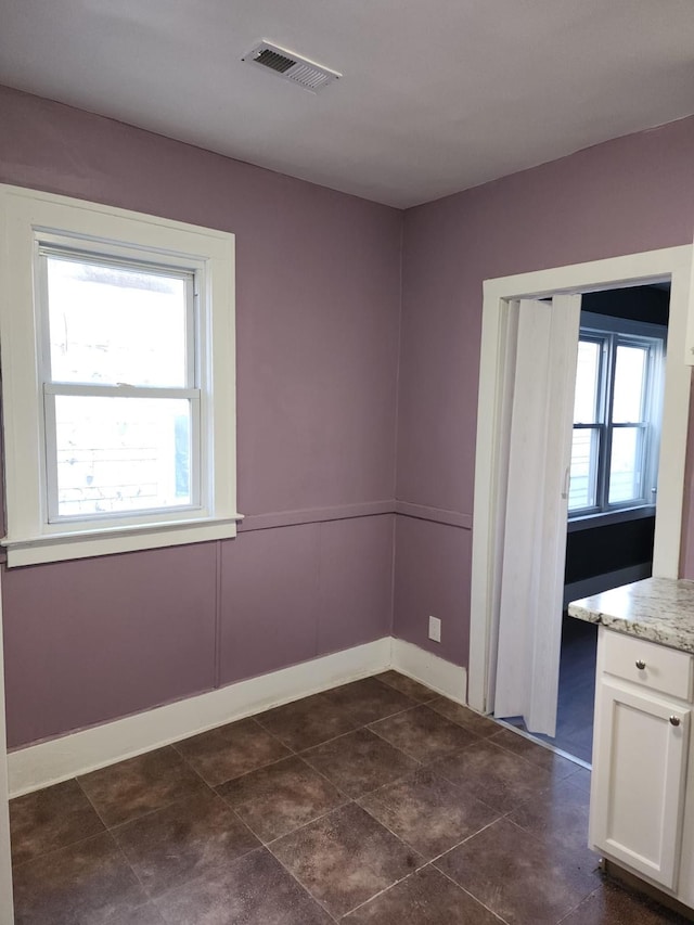 spare room with visible vents, plenty of natural light, and baseboards