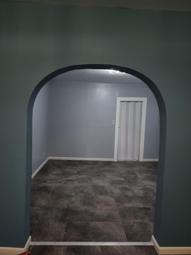 unfurnished room with baseboards and arched walkways