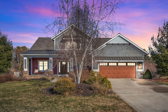 craftsman house with driveway, a standing seam roof, an attached garage, a front lawn, and metal roof