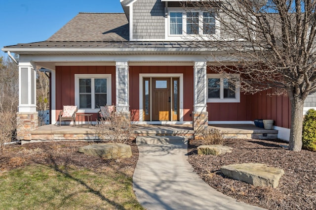 view of front facade with board and batten siding, covered porch, and roof with shingles