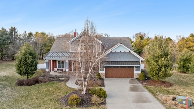 view of front of property featuring a standing seam roof, driveway, and metal roof