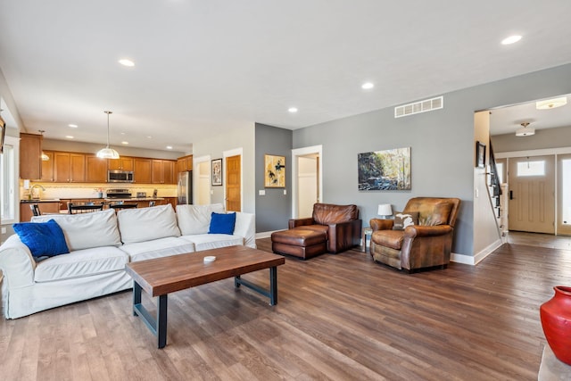 living room with recessed lighting, visible vents, baseboards, and wood finished floors