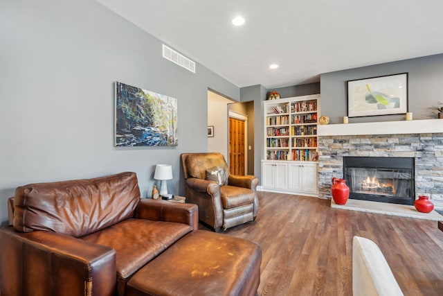 living room with wood finished floors, recessed lighting, a fireplace, and visible vents