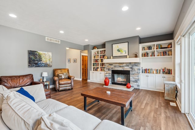 living area with a fireplace, recessed lighting, wood finished floors, and visible vents