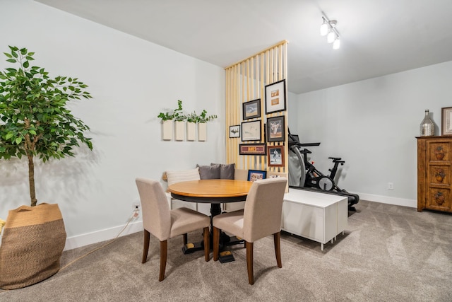 dining space with rail lighting, baseboards, and carpet floors