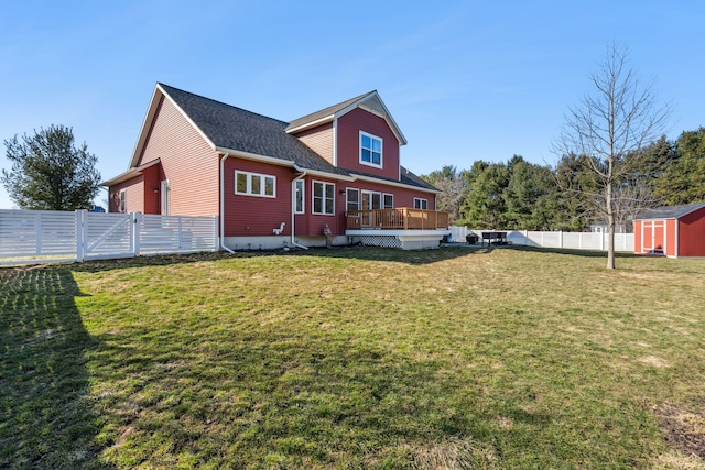 rear view of house featuring an outbuilding, a shed, a wooden deck, a yard, and a fenced backyard