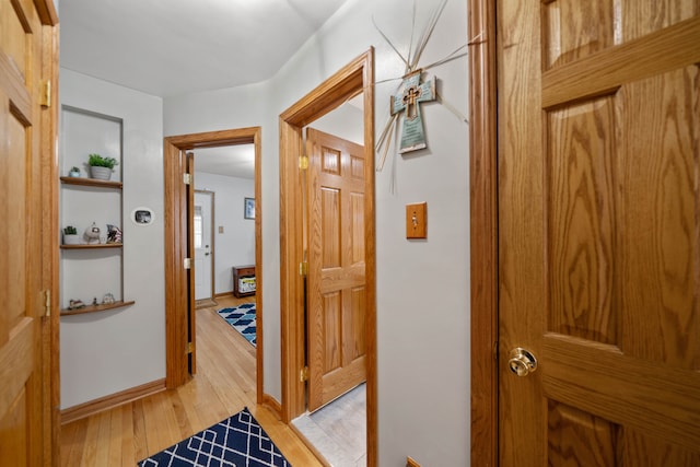 hall with light wood-style floors and baseboards