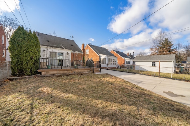 rear view of house featuring a deck, a yard, fence, and a residential view