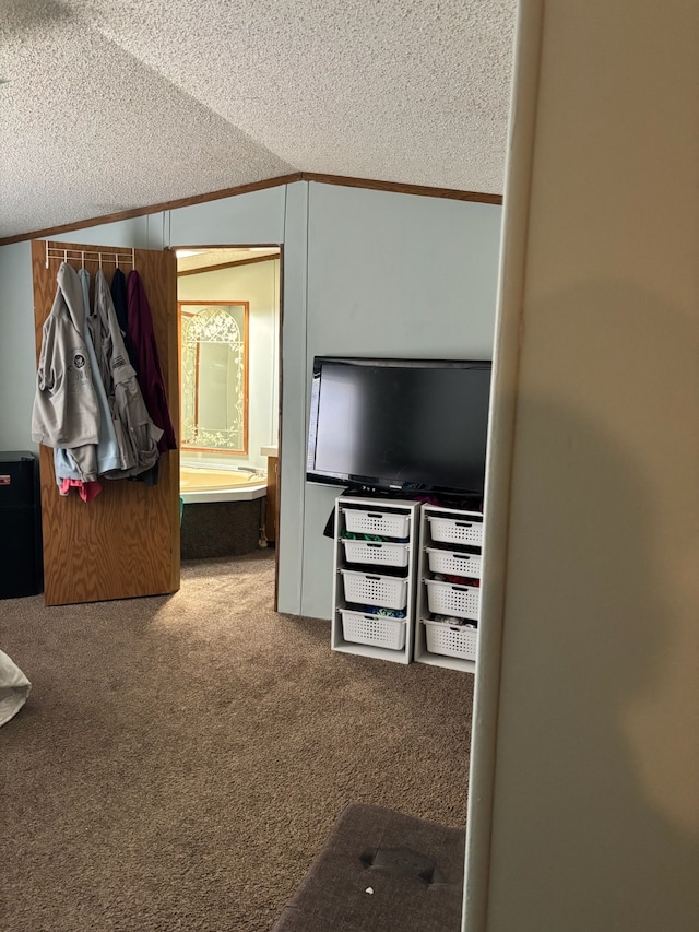 interior space with a textured ceiling, connected bathroom, carpet, crown molding, and vaulted ceiling