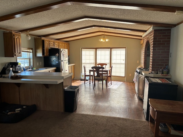 kitchen with lofted ceiling with beams, stainless steel appliances, light countertops, a textured ceiling, and a notable chandelier