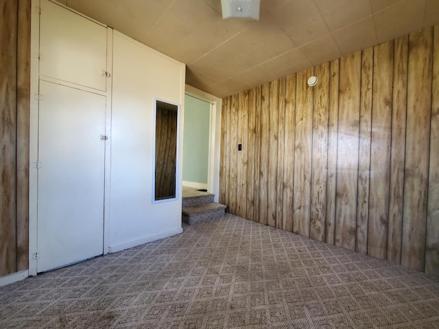 carpeted empty room with wooden walls