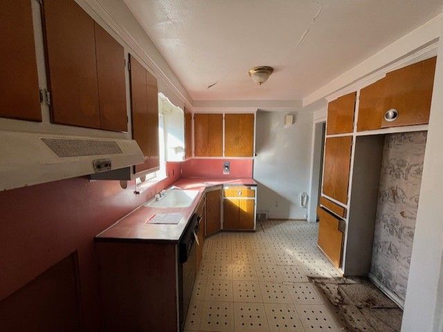kitchen featuring light floors, brown cabinets, and a sink