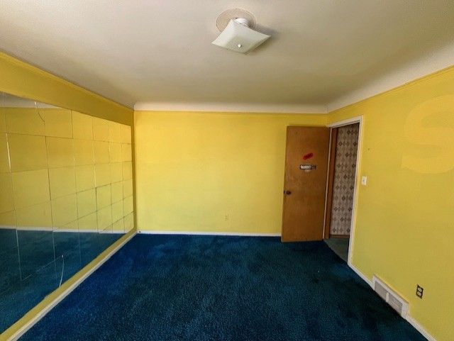 spare room featuring visible vents and dark carpet