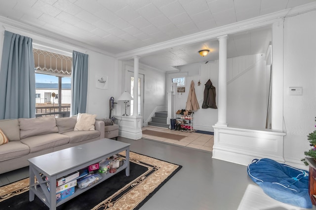 living area featuring stairway, finished concrete flooring, crown molding, and ornate columns