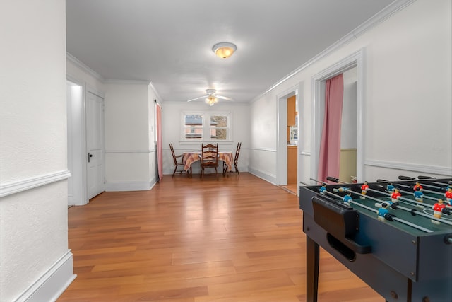 rec room featuring a ceiling fan, light wood-type flooring, and ornamental molding