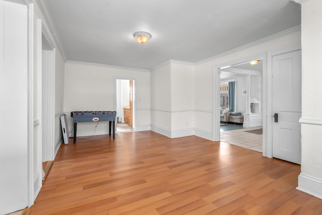 unfurnished room featuring light wood-style flooring, baseboards, and ornamental molding