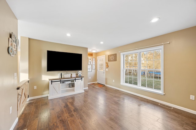 unfurnished living room with dark wood-type flooring, recessed lighting, baseboards, and visible vents